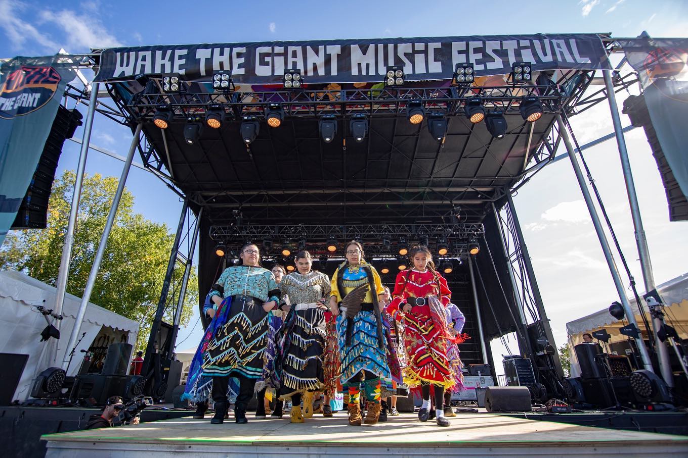 Four Indigenous women on stage in traditional dress at Wake the Giant Music Festival