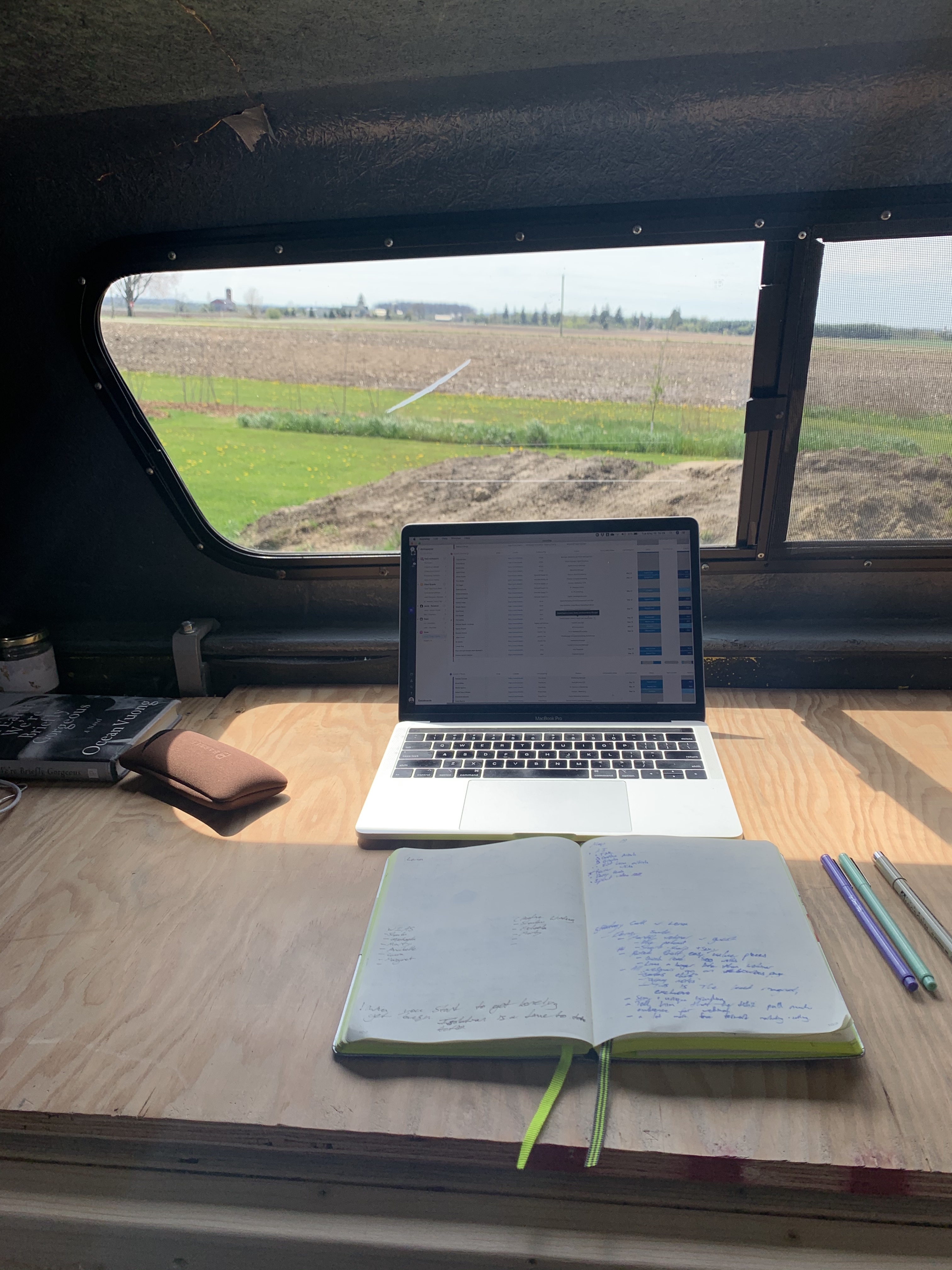 RV work from home set up with a laptop and an open book with views of a field.