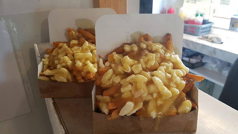 Two giant orders of poutine on a countertop.