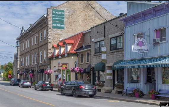 a pretty street in Merrickville with old stone buildings and hanging pots of flowers, with the largest building sporting a Baldachin Inn sign.