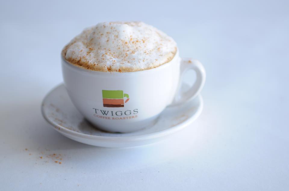 a latte in a small white cup with a Twiggs logo on it