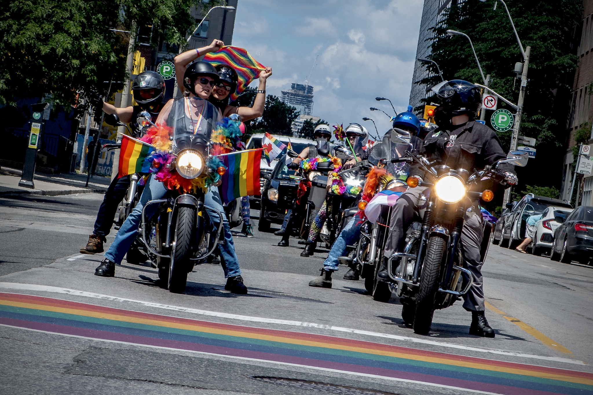 The Amazons motorcycle group in a 2020 Pride parade; two lines of motorcycles and riders, decorated with rainbow flags, riding down a city street