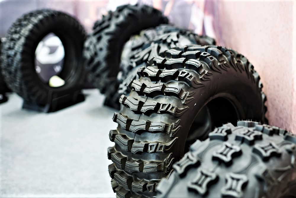 4 ATV tires sitting against a light pink wall on a grey floor