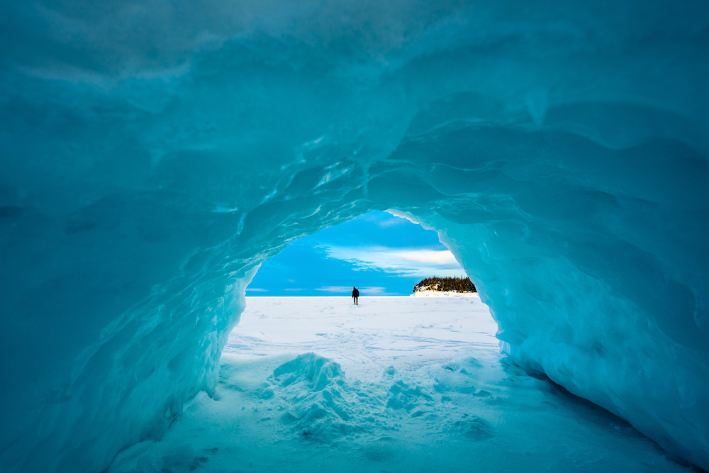 View from inside an ice cave with figure standing on ice.