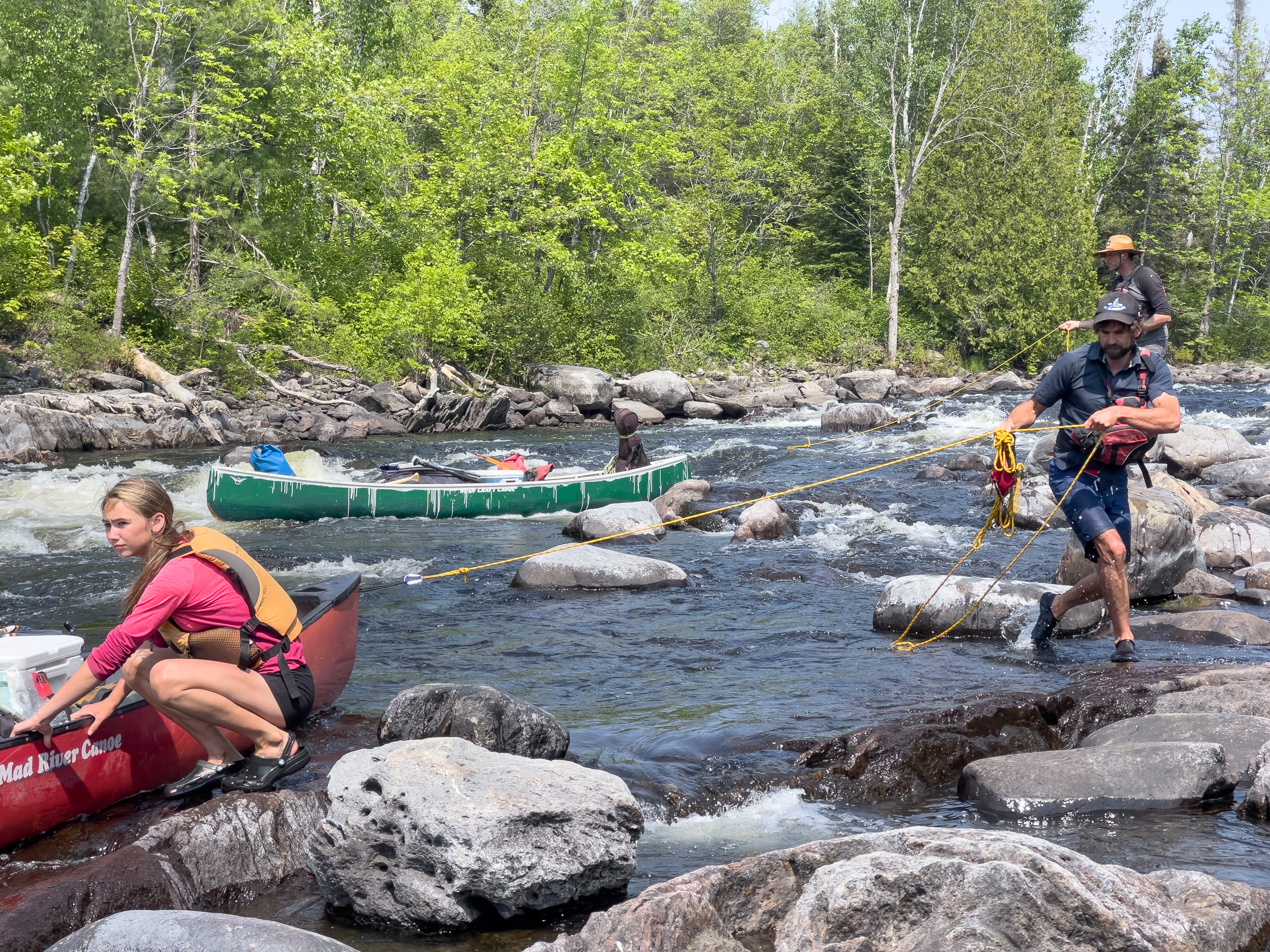people using rope to move canoes through rapids