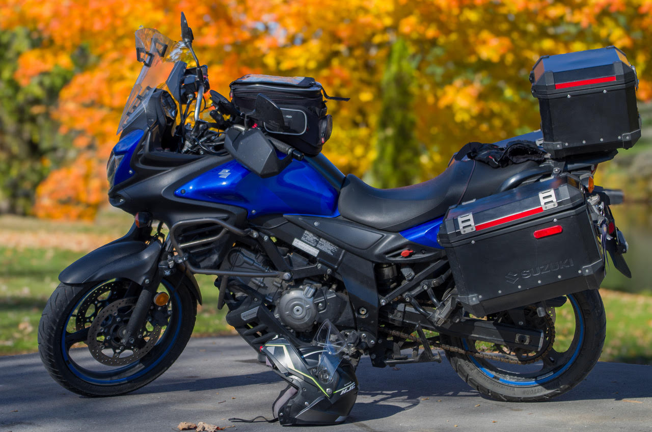 a blue motorcycle parked in front of bright orange and green autumn trees