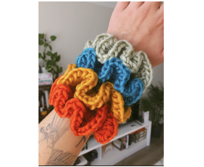 4 colourful crocheted scrunchies on a wrist