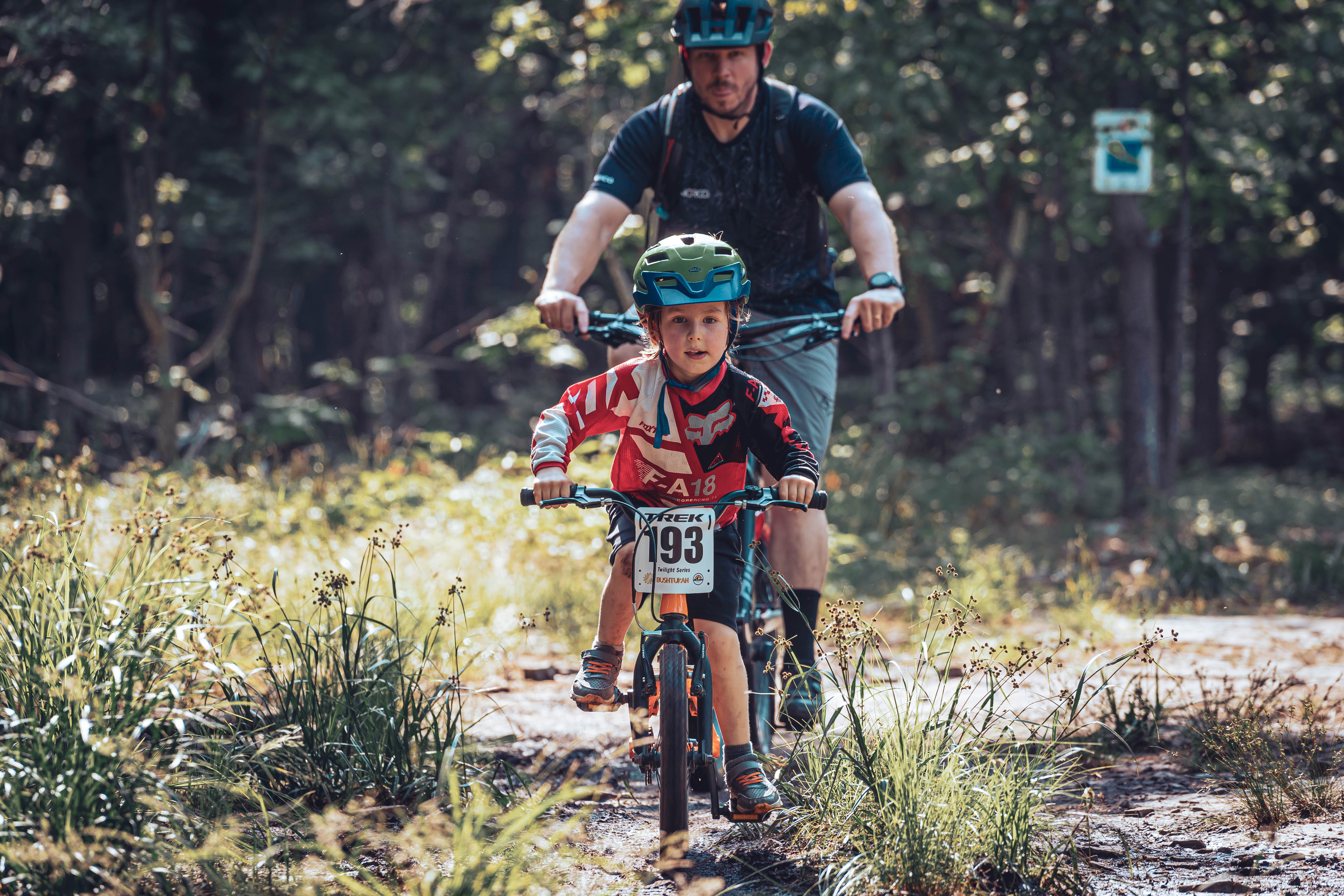 man and boy ride bikes along a forest path