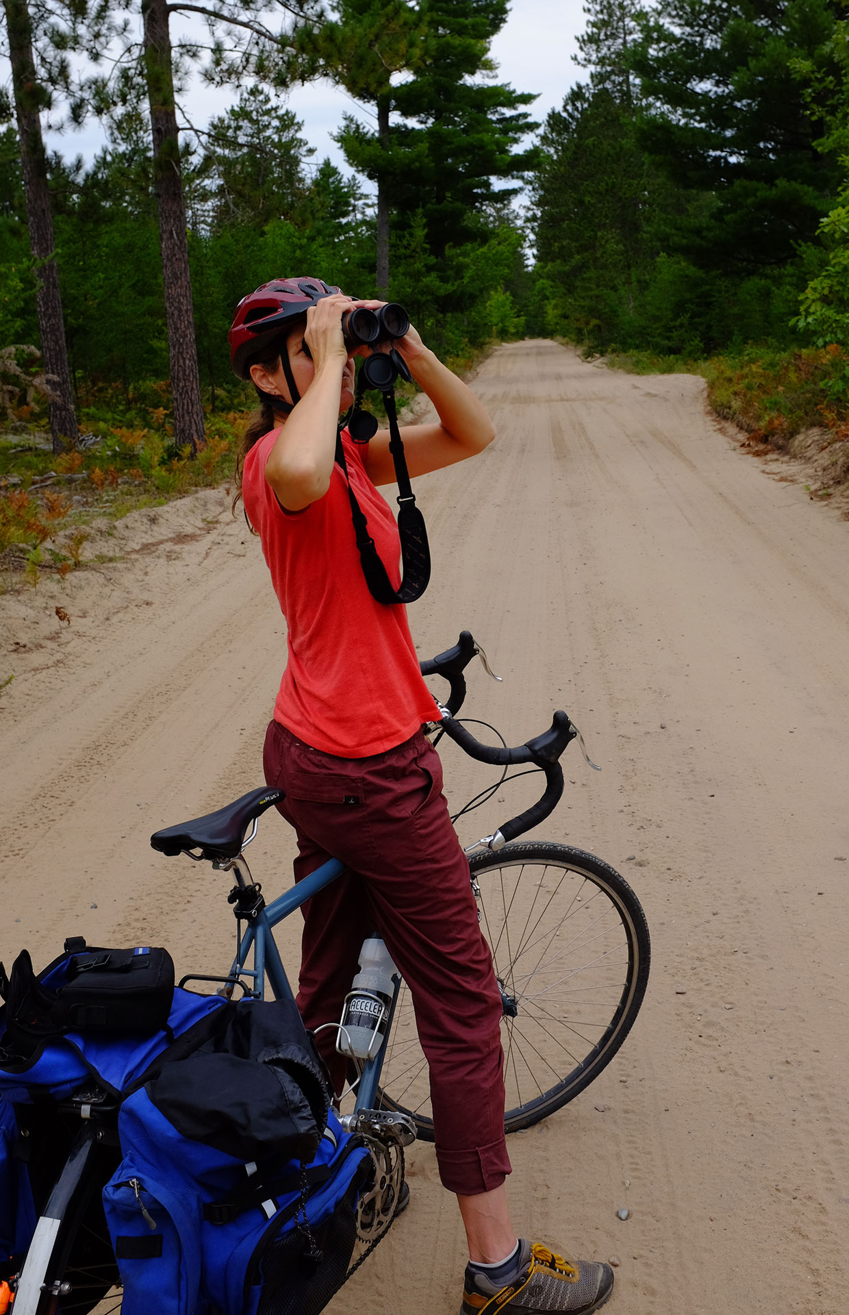 a woman stops on her bicycle to use binoculars for birdwatching