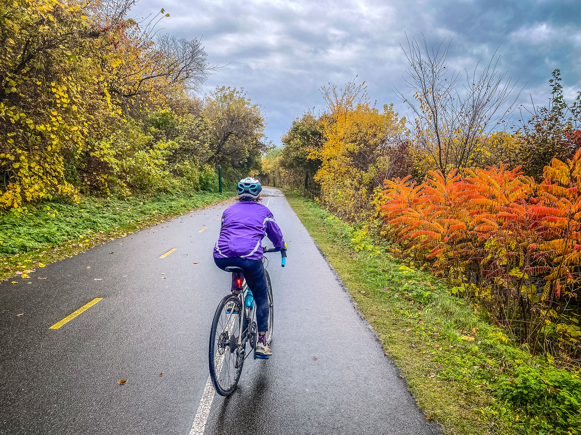 a person riding a bike down a damp path in fall