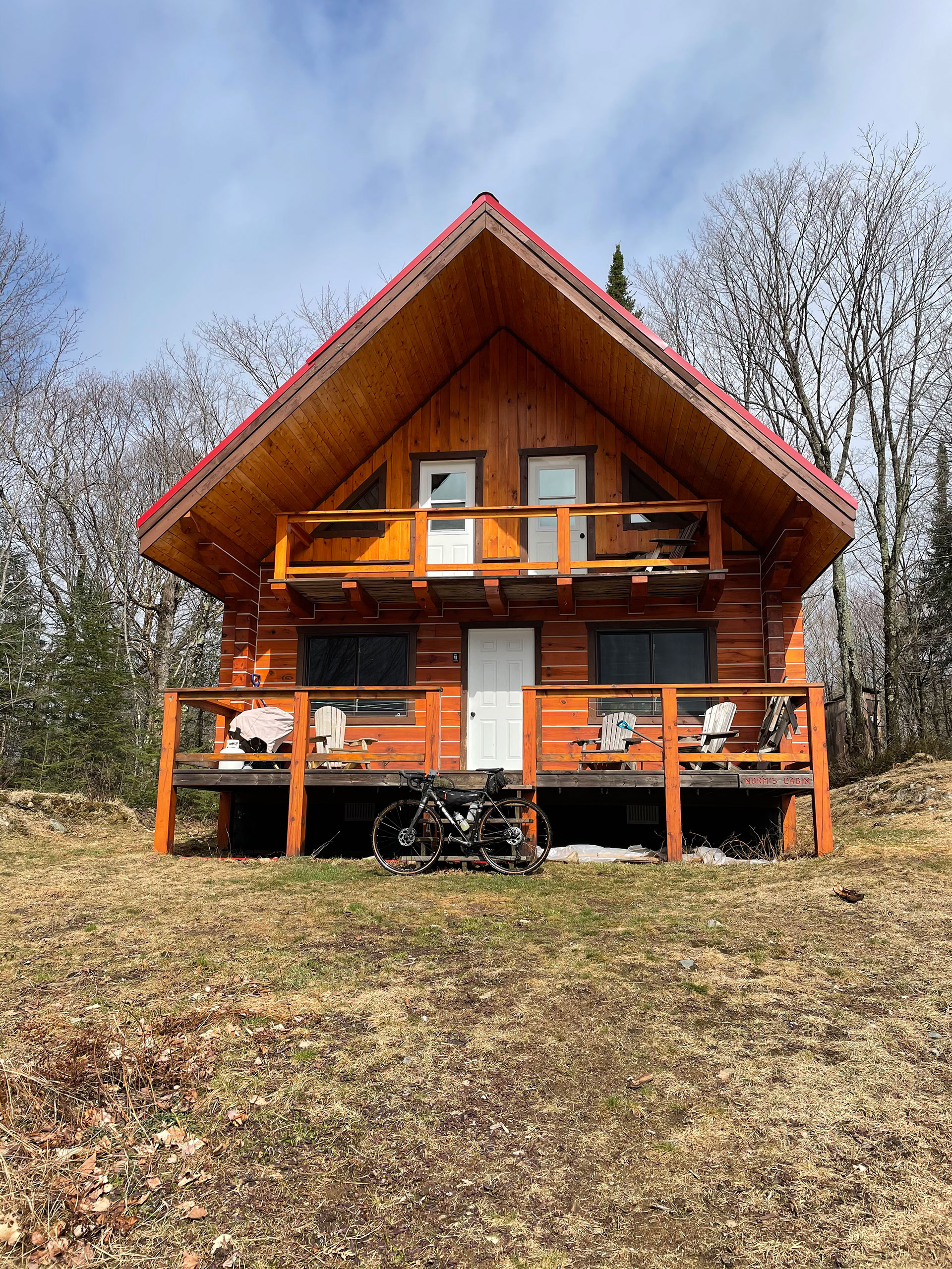 bicycle propped against the front deck of a chalet in spring