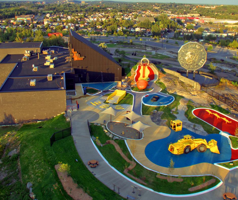 an aerial view of the grounds of Dynamic Earth, showing several of the outdoor attractions, including an outdoor play park and the Big Nickel monument