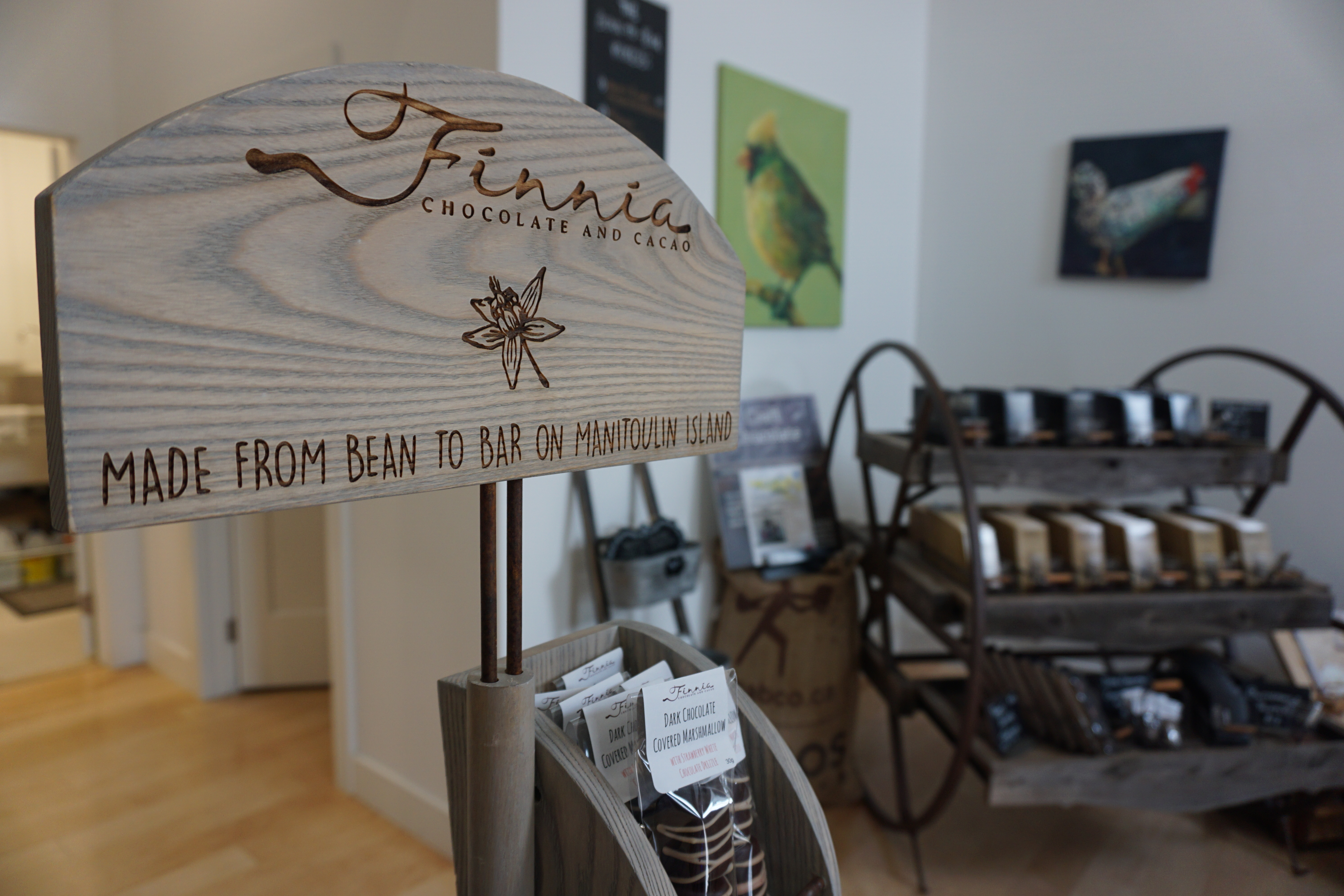a wooden sign over gourmet chocolate bars that reads "Finnia chocolate and cacao: made from bean to bar on Manitoulin Island".