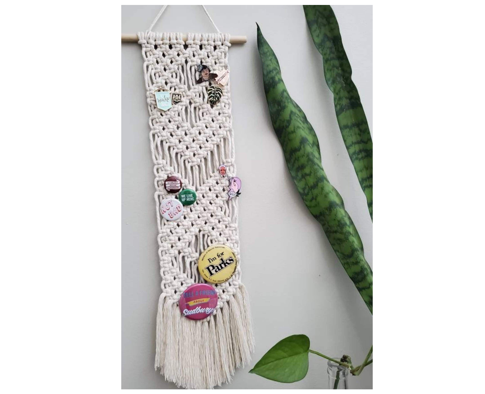 a white macrame pin holder displaying pins and buttons