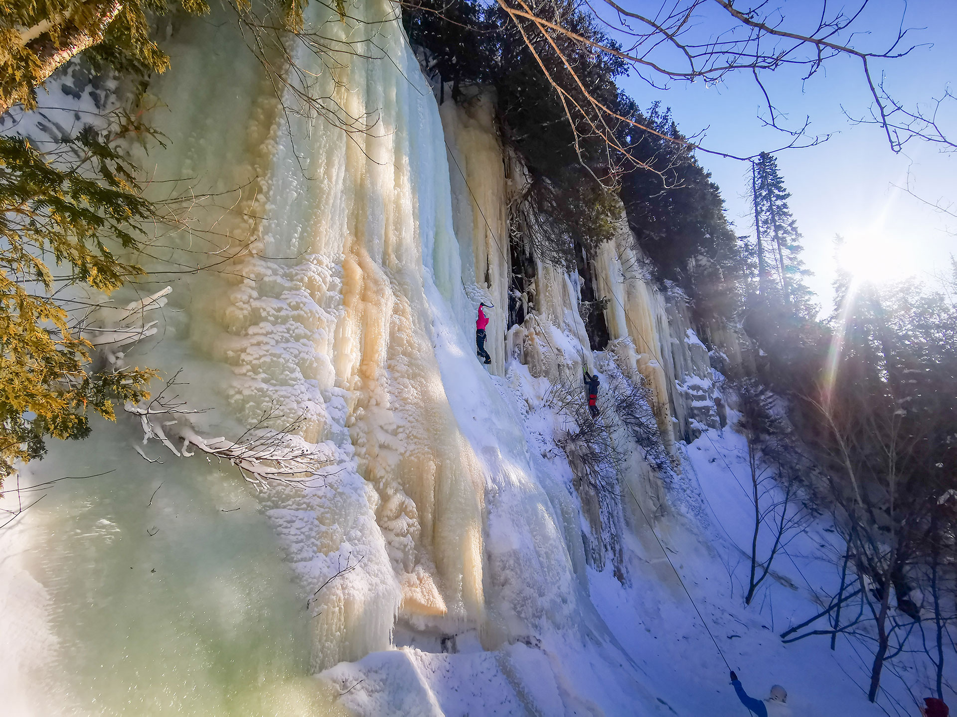 person climbs an ice waterfall in winter
