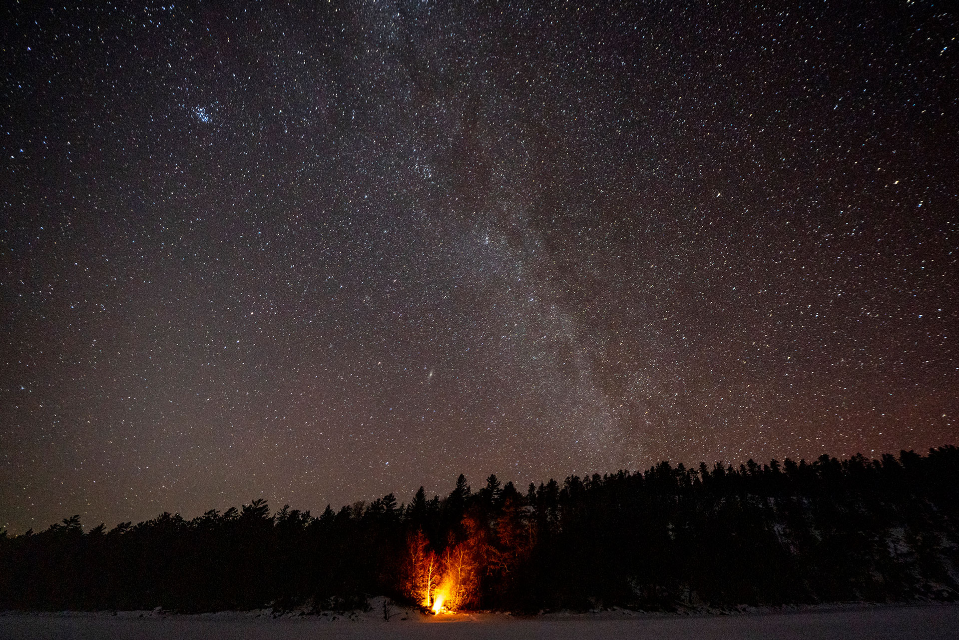 a dark sky with Milky Way over a campfire