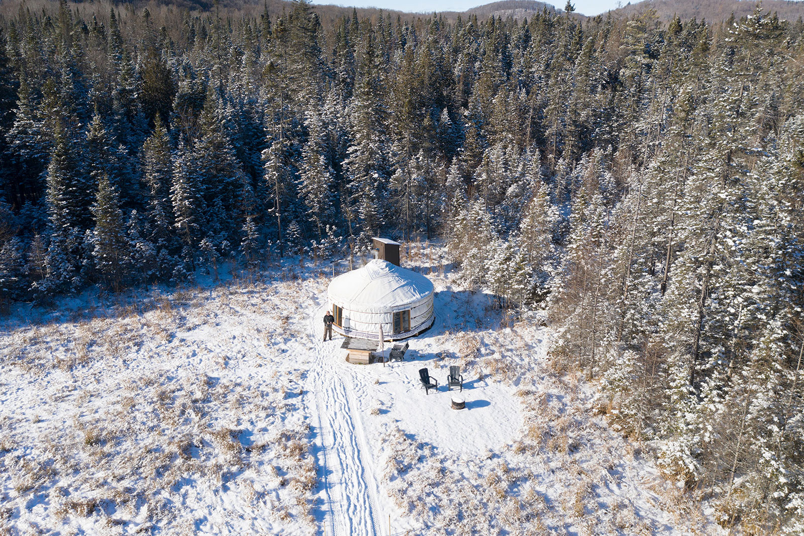 overhead view of white yurt surrounded by wintry trees