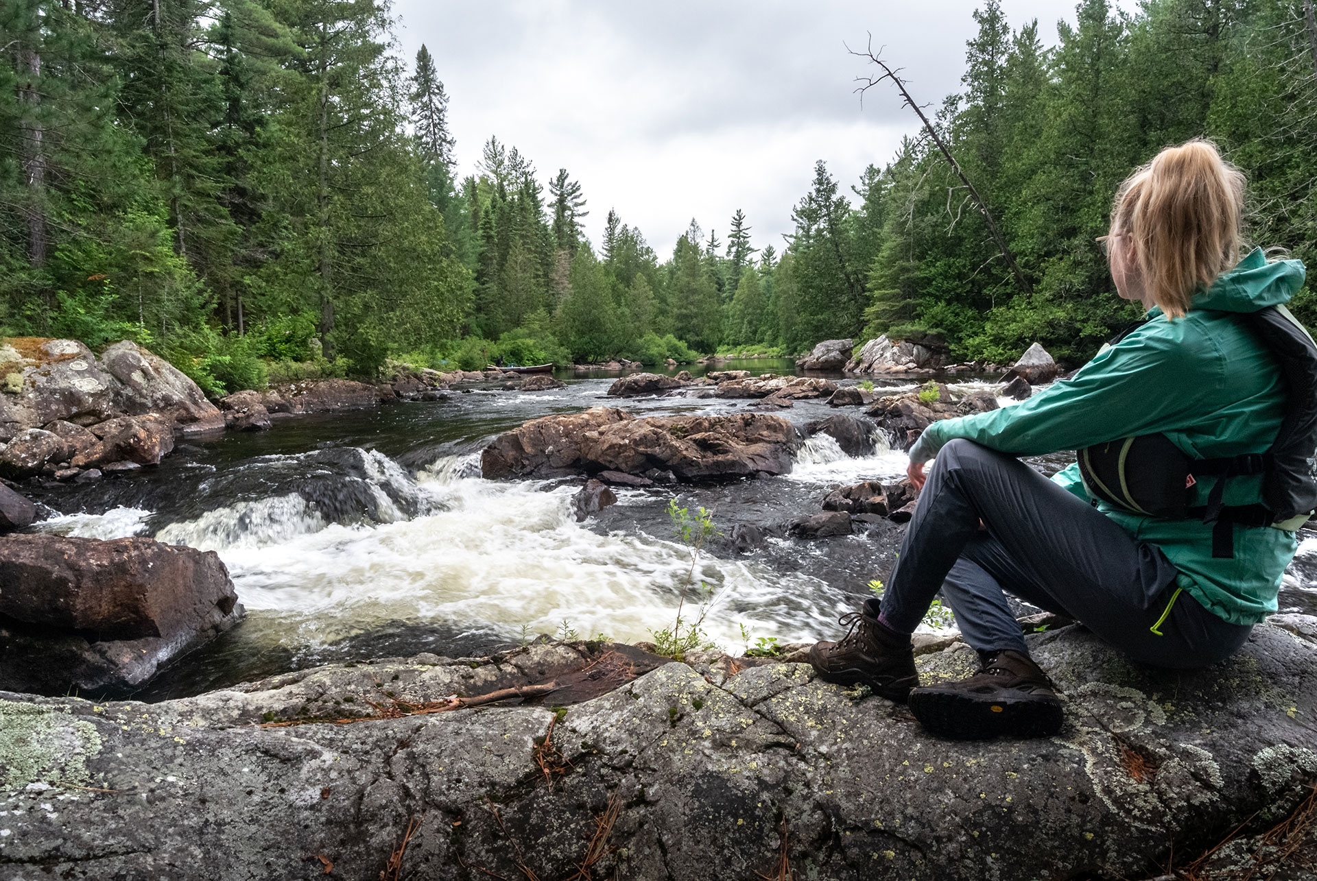 woman sits and looks at rapids on a river