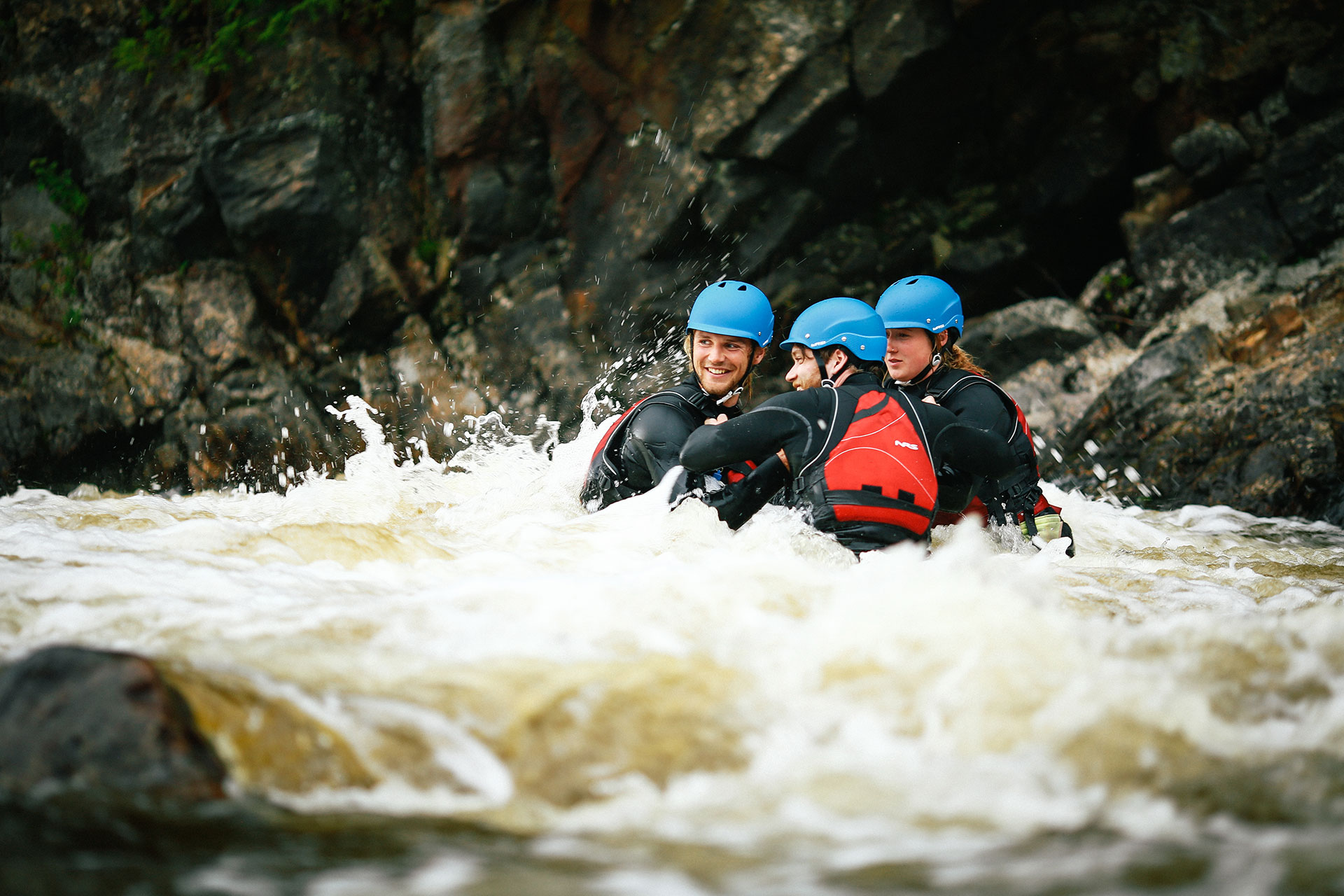 three whitewater rescue students crouch in the river as they learn their lessons