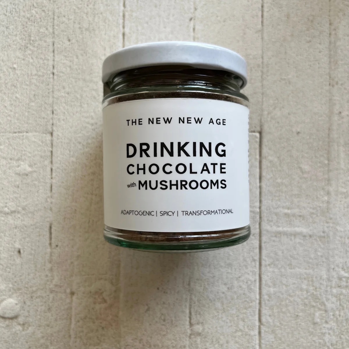 jar with white lid and label that reads "drinking chocolate with mushrooms" on a white wooden background