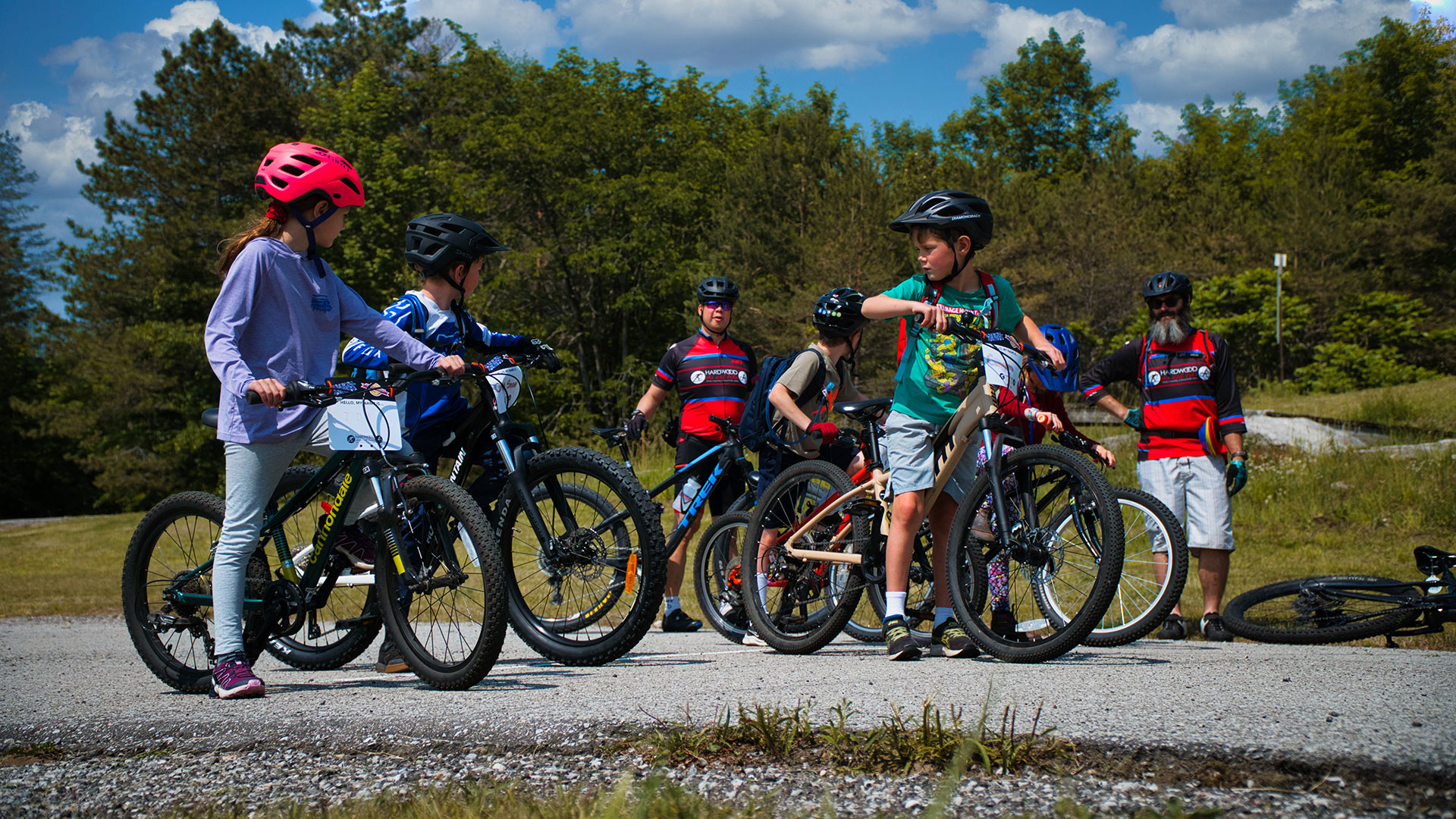 a bike instructor teaches a group of young cyclists while on a ride