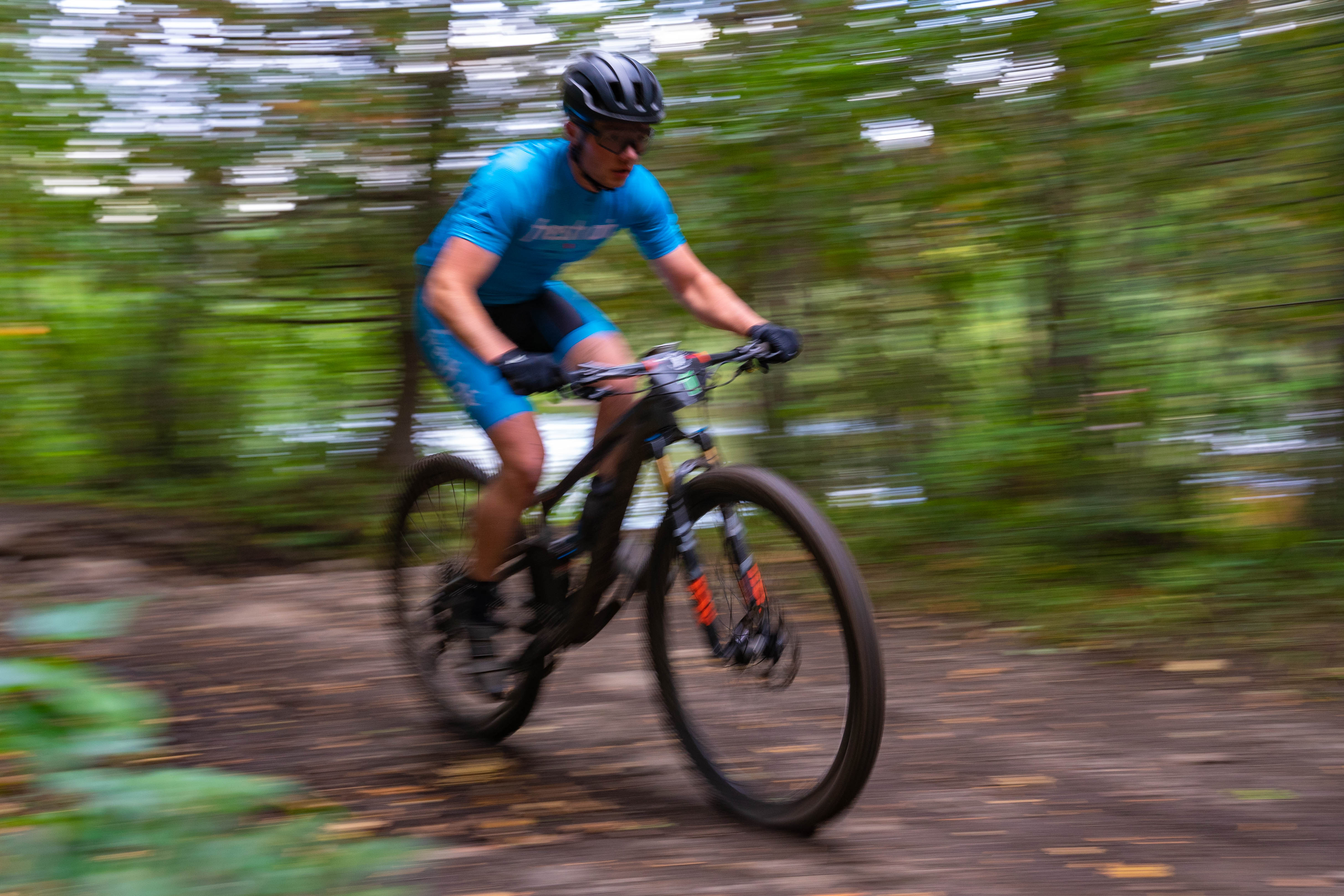 action shot of a man riding his mountain bike along a forest trail
