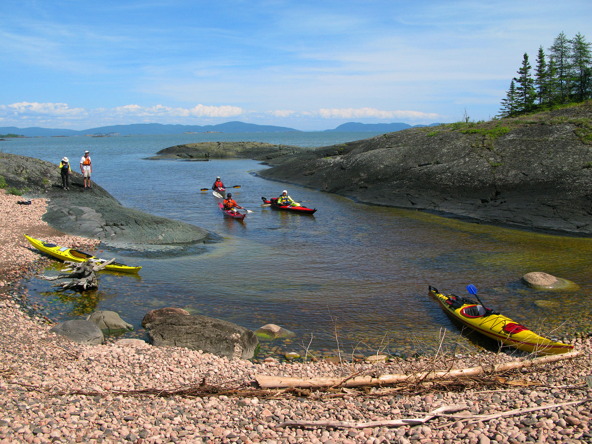 a group of kayakers prepare to set out from a sheltered bay into Lake Superior