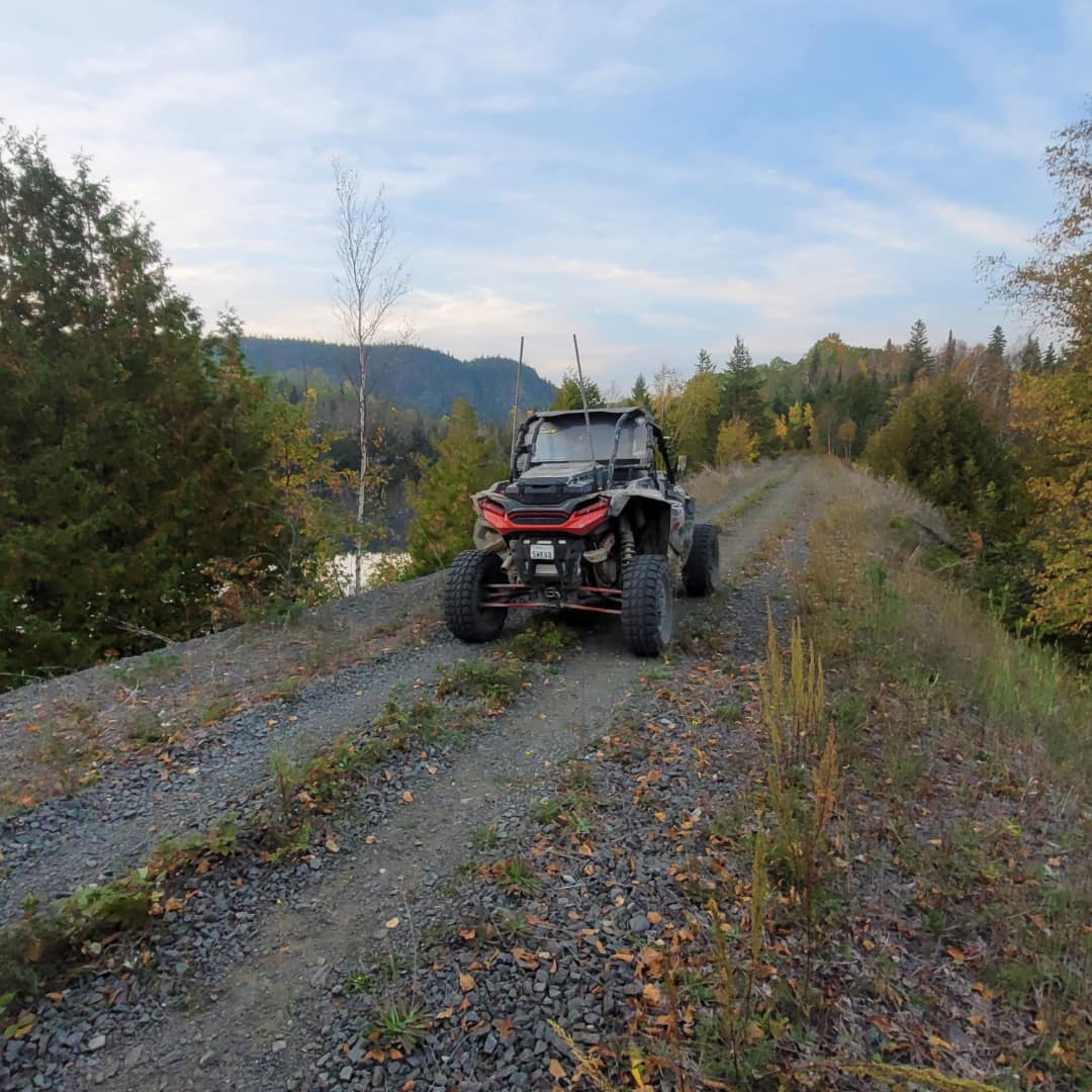 An ATV on a gravel trail lined with autumn trees