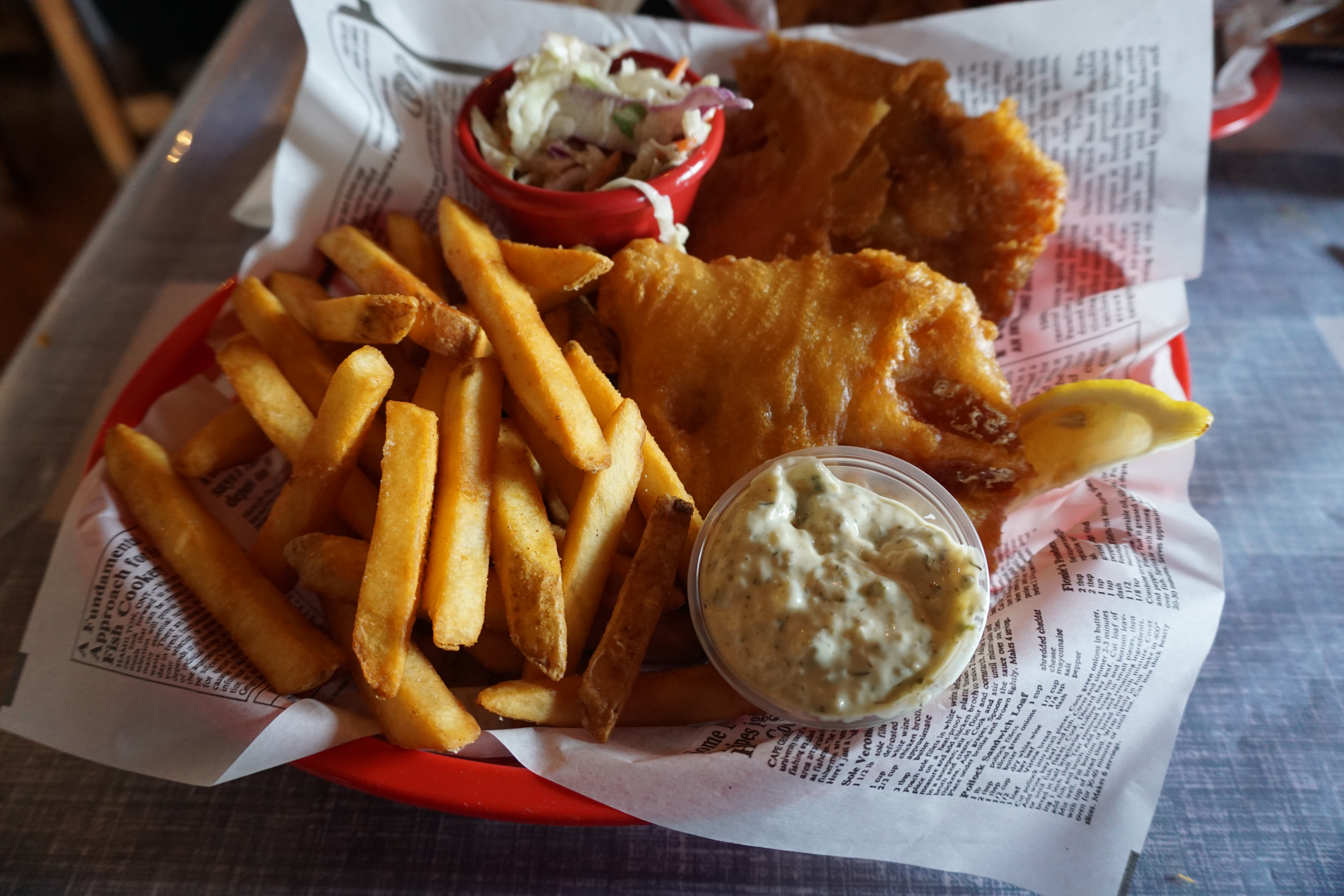 an order of fish and chips with coleslaw and tartar sauce.
