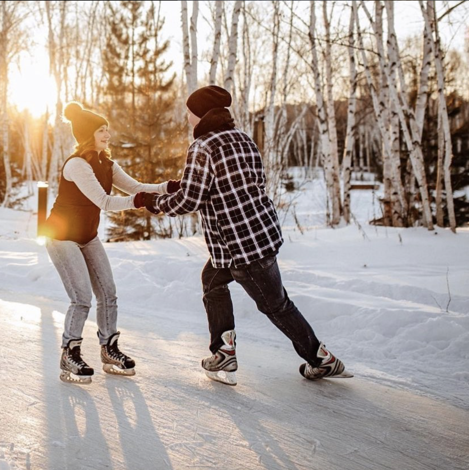 a man and woman facing each other and smiling, skating down an ice trail at sunset