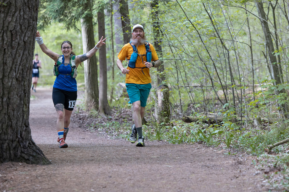 Man and woman running on a trail in the woods
