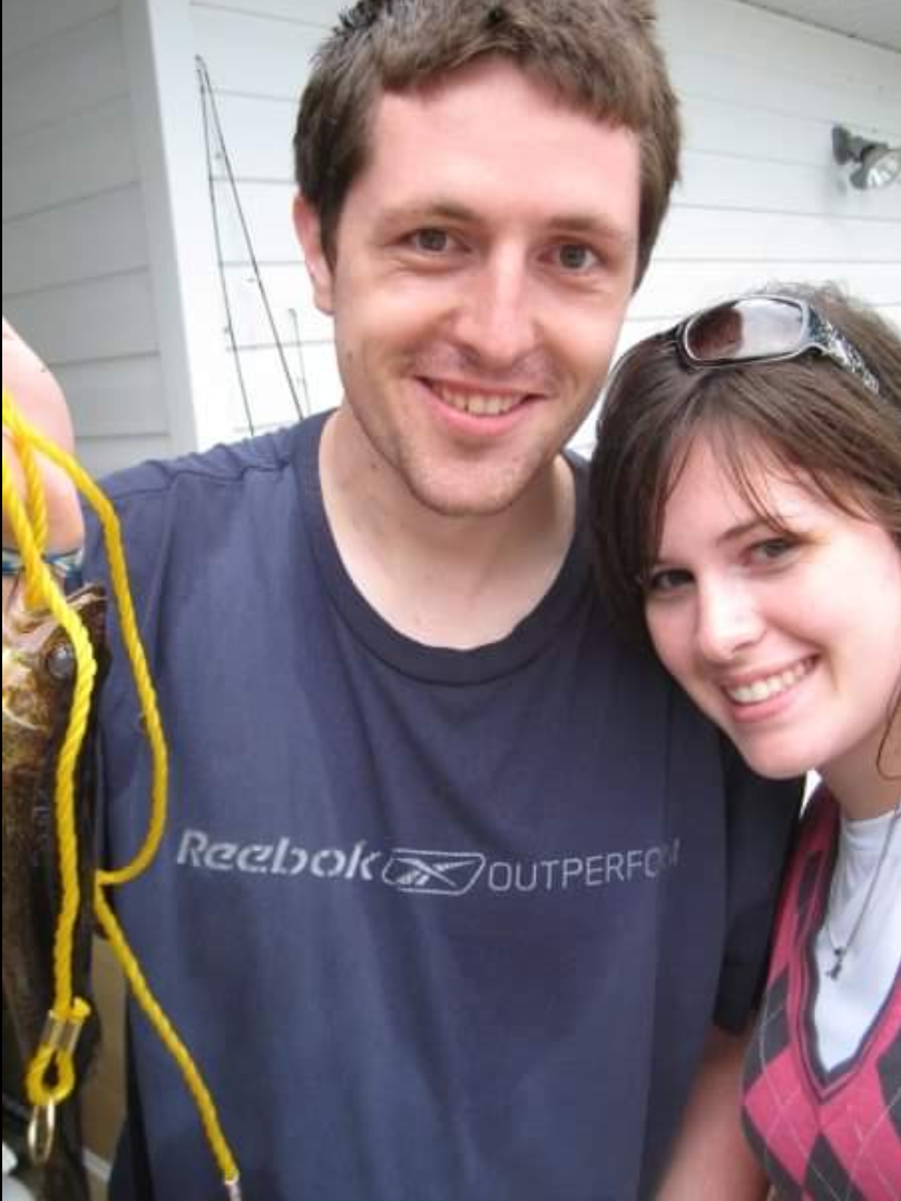 A young man holding a bundle of yellow rope and a young woman, both with sunglasses on their heads and smiling into the camera. 