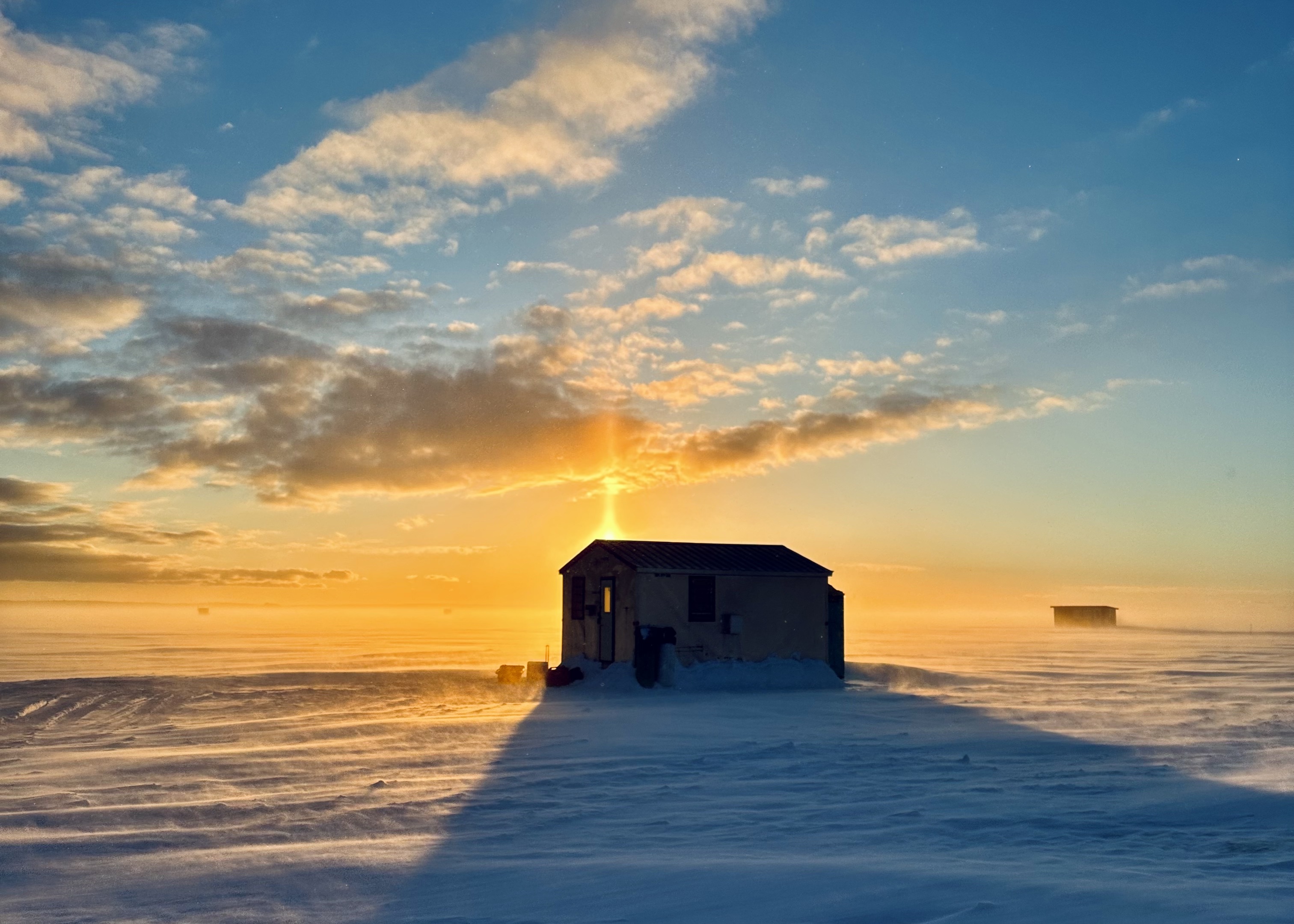 Ice hut silhouetted in the setting sun on frozen Lake Nipissing