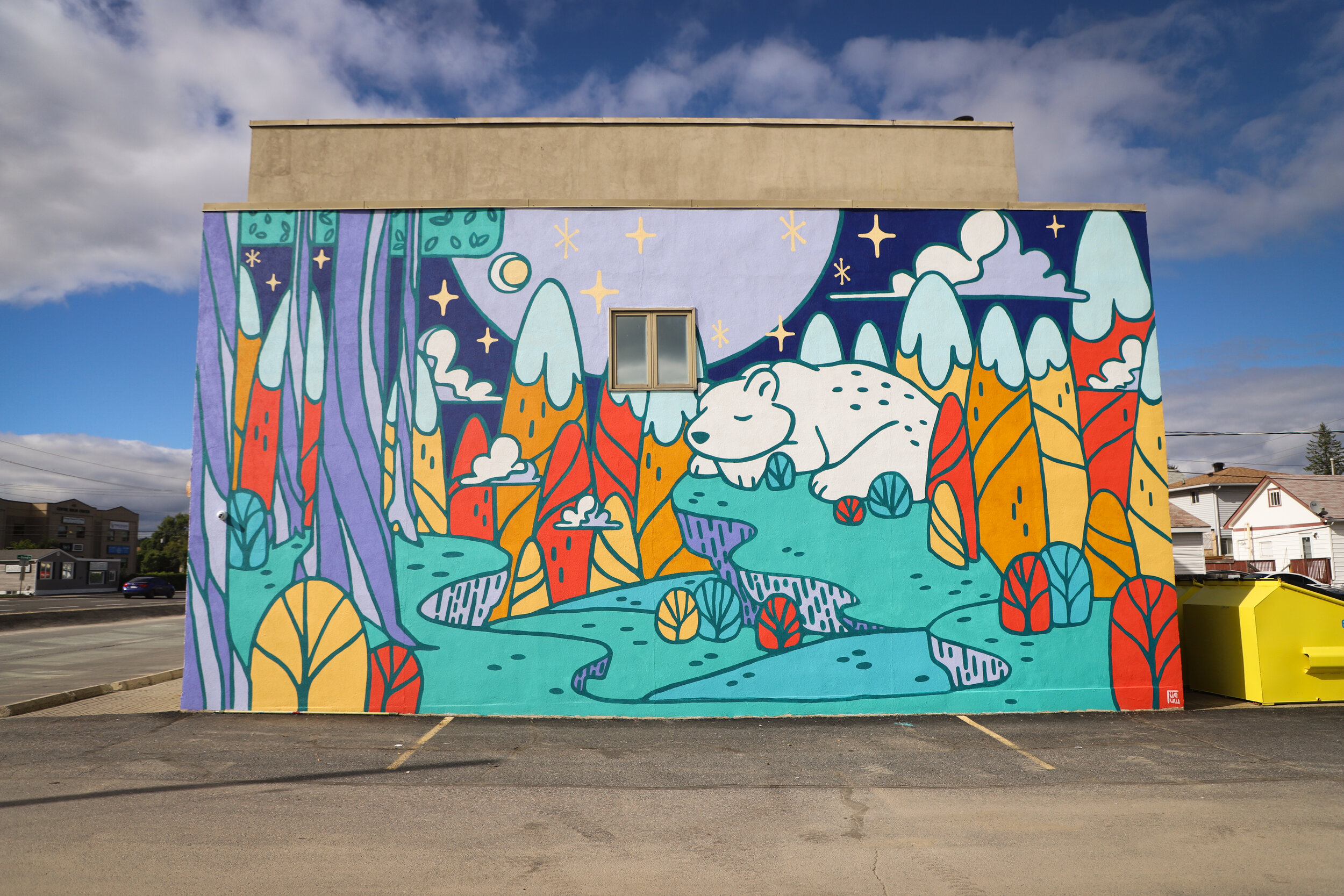 an colourful outdoor mural in Sudbury of a sleeping bear in a forest 