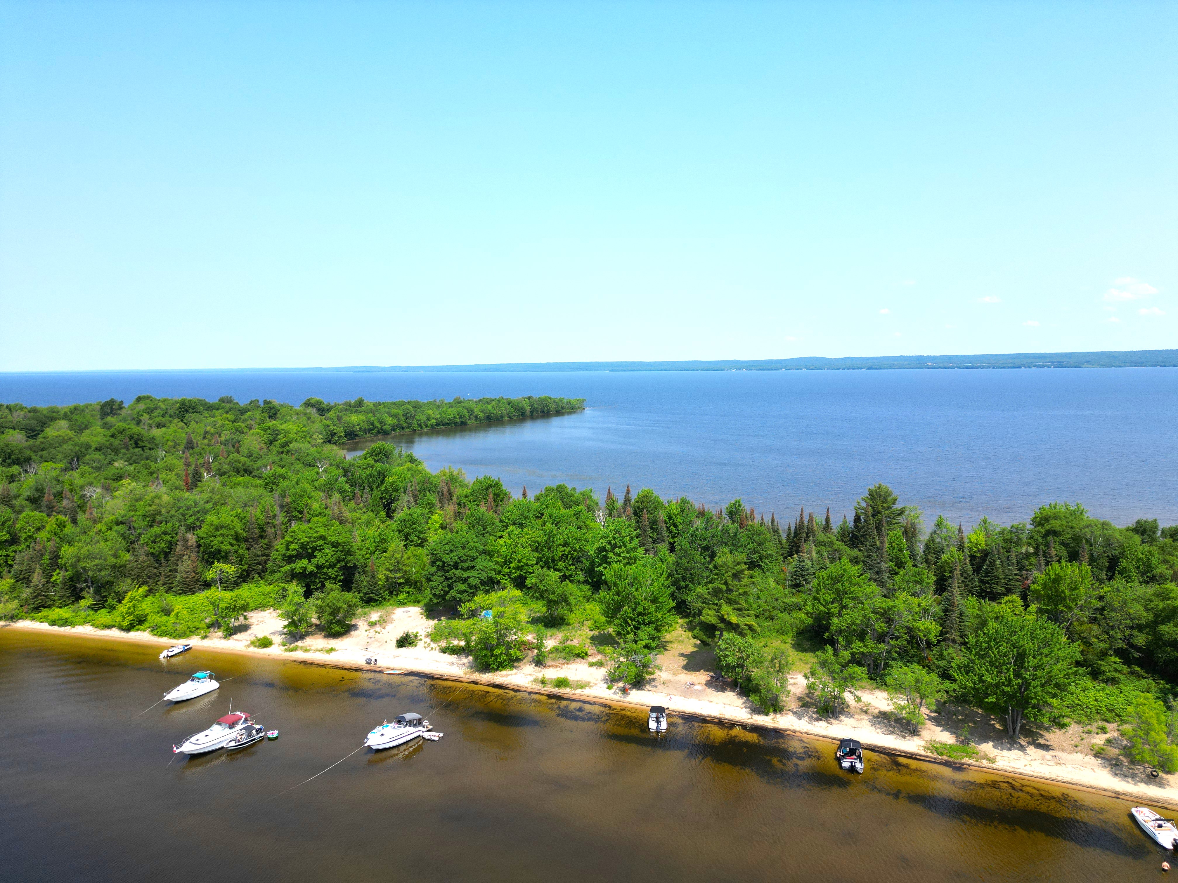Great Manitou Island a bird's eye view of a lake with boats and a sandpit with green trees. 