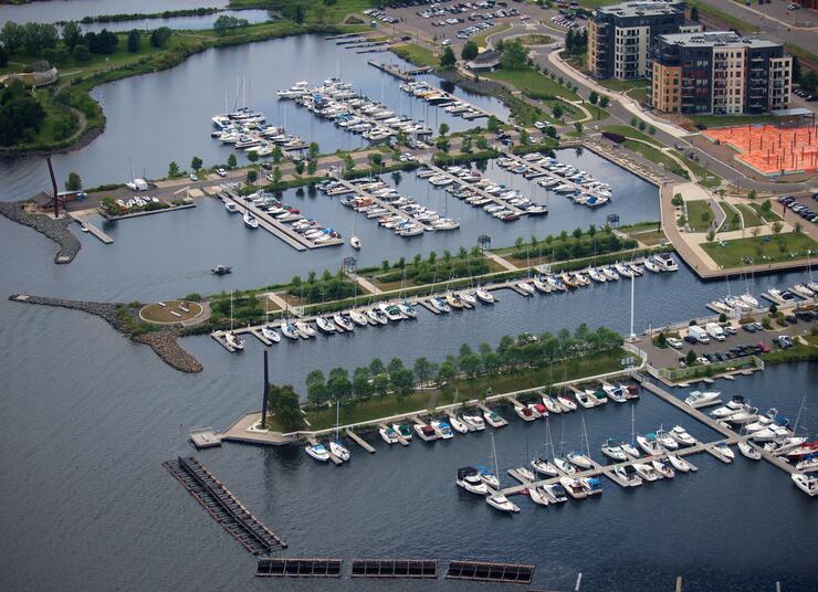 an aerial shot of Prince Arthur's Landing; a large lake marina with numerous boats in slips, surrounded by greenery on the shores.