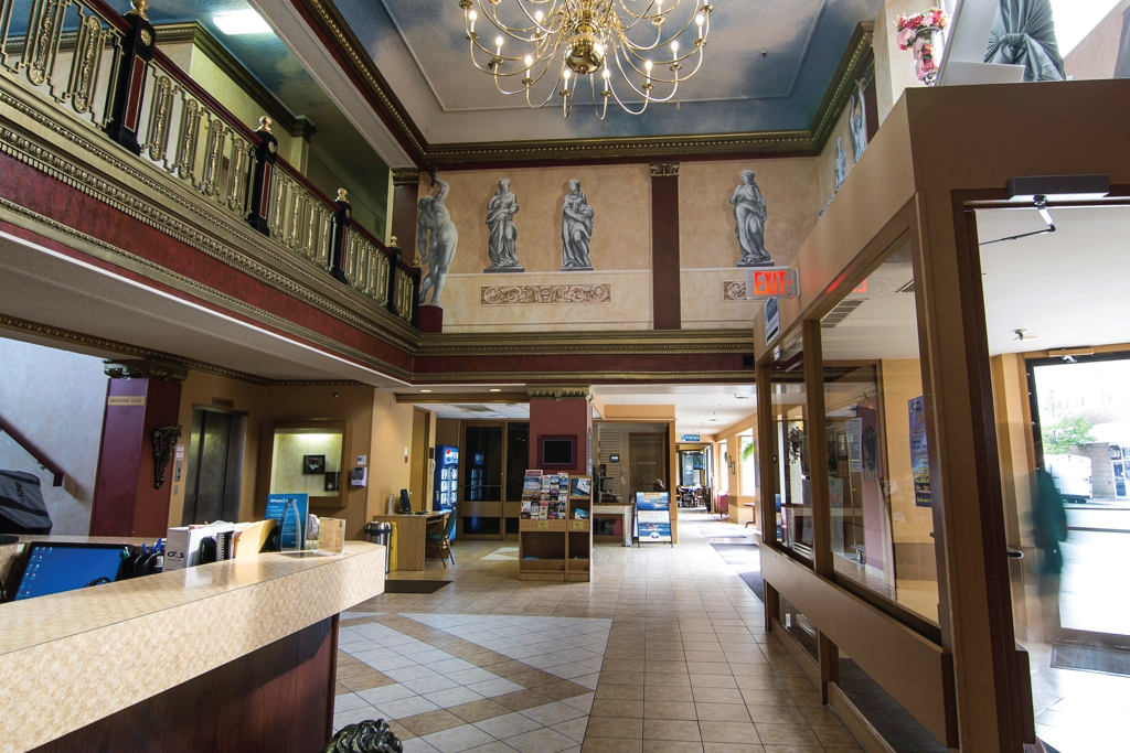 The Prince Arthur Waterfront Hotel lobby; a huge, elegant room with glowing chandelier, polished marble floor, dark wood trim and stone statues in alcoves near the ceiling. 