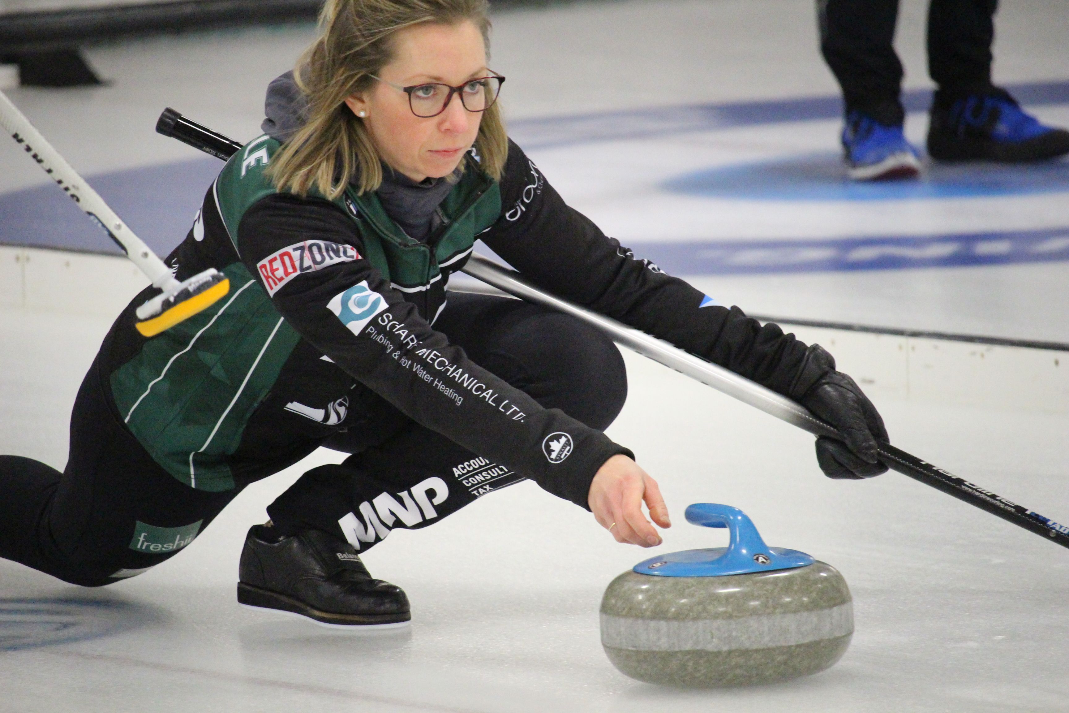 Curler Krista McCarville throwing a curling rock with a look of focused determination on her face.