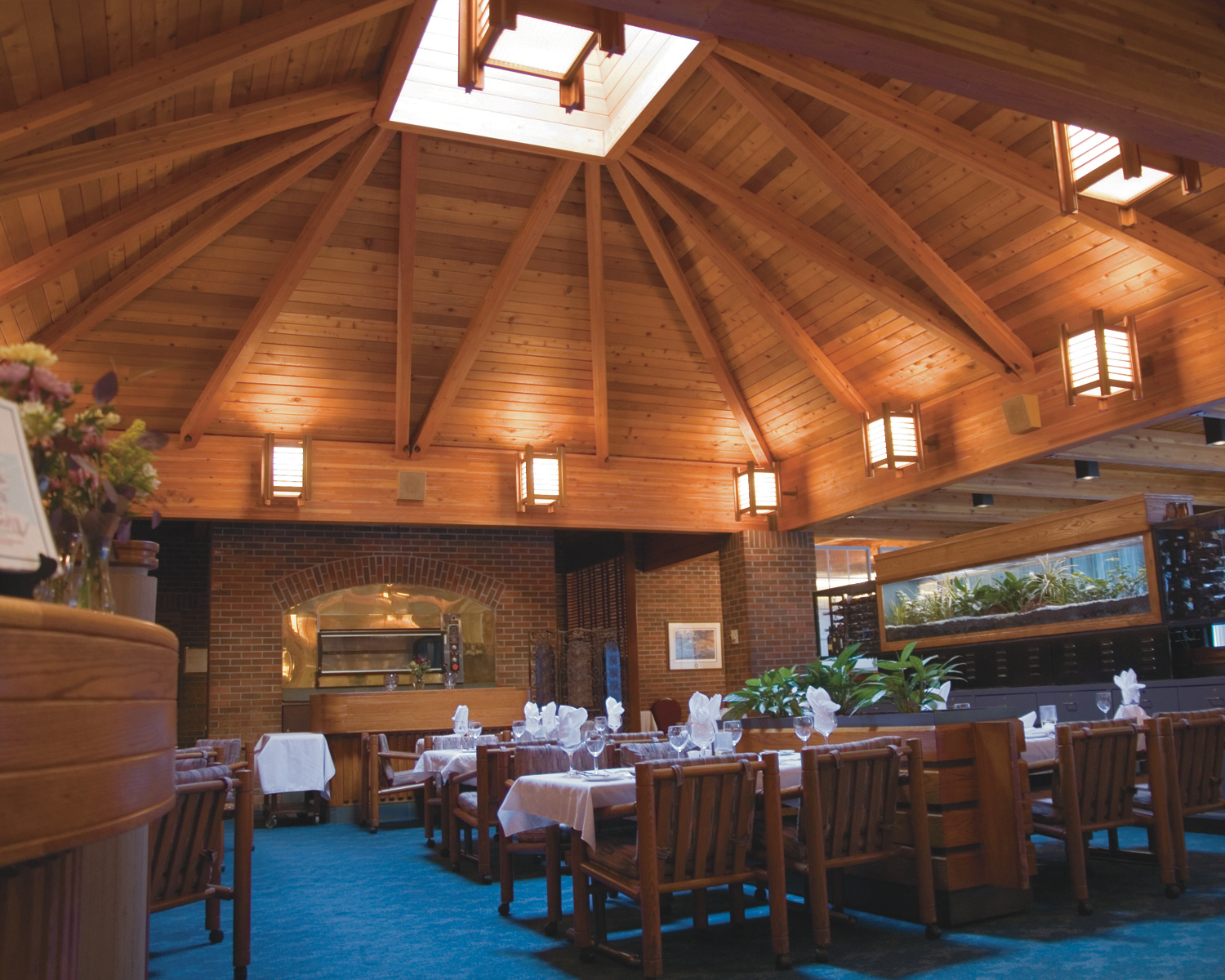 The dining room at the Valhalla in Thunder Bay; a large, elegant, warmly-lit dining room with wooden chairs and a high-peaked ceiling made of wooden beams.