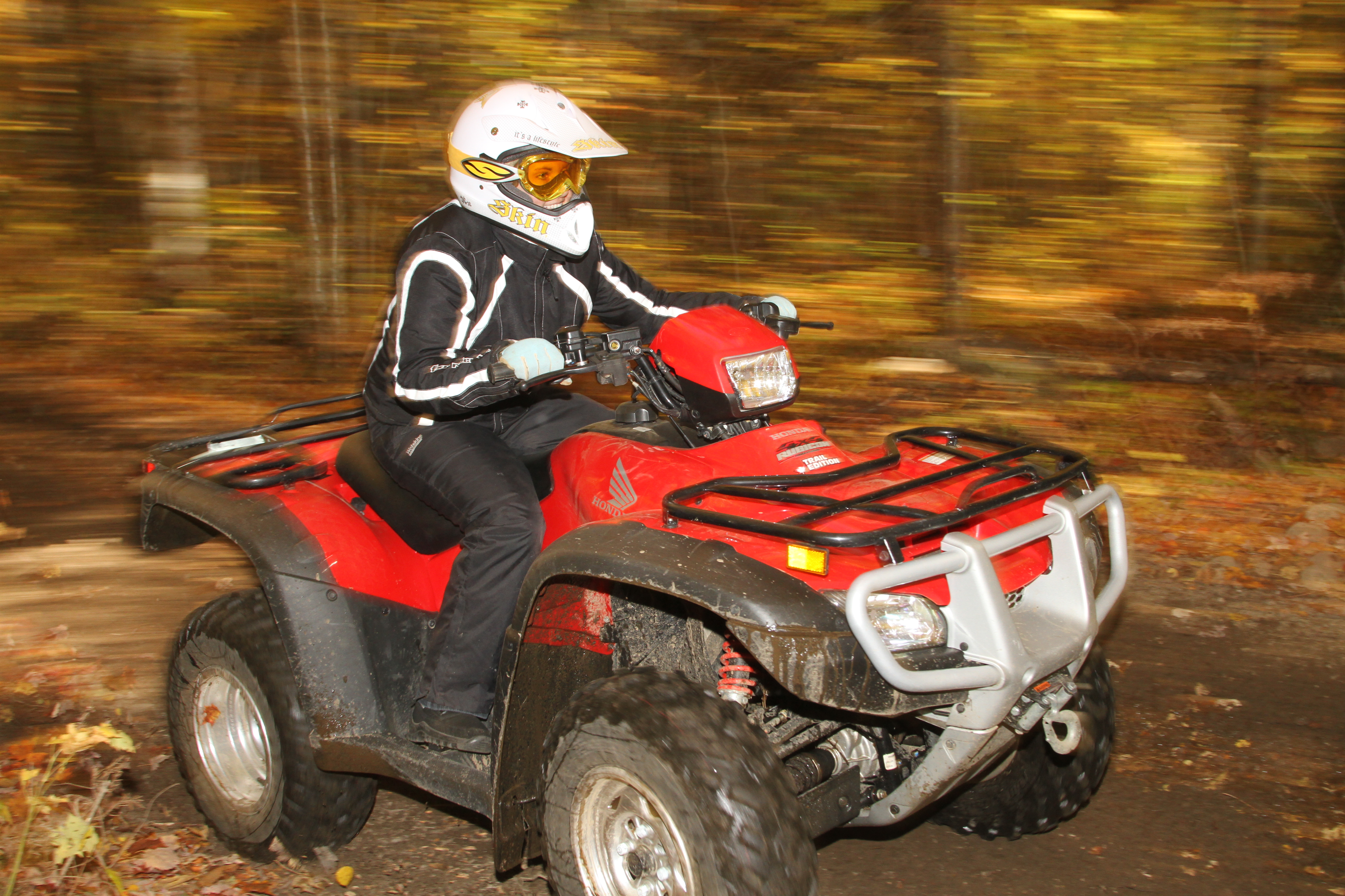 A person on an ATV driving down a forest trail, the forest blurring by.