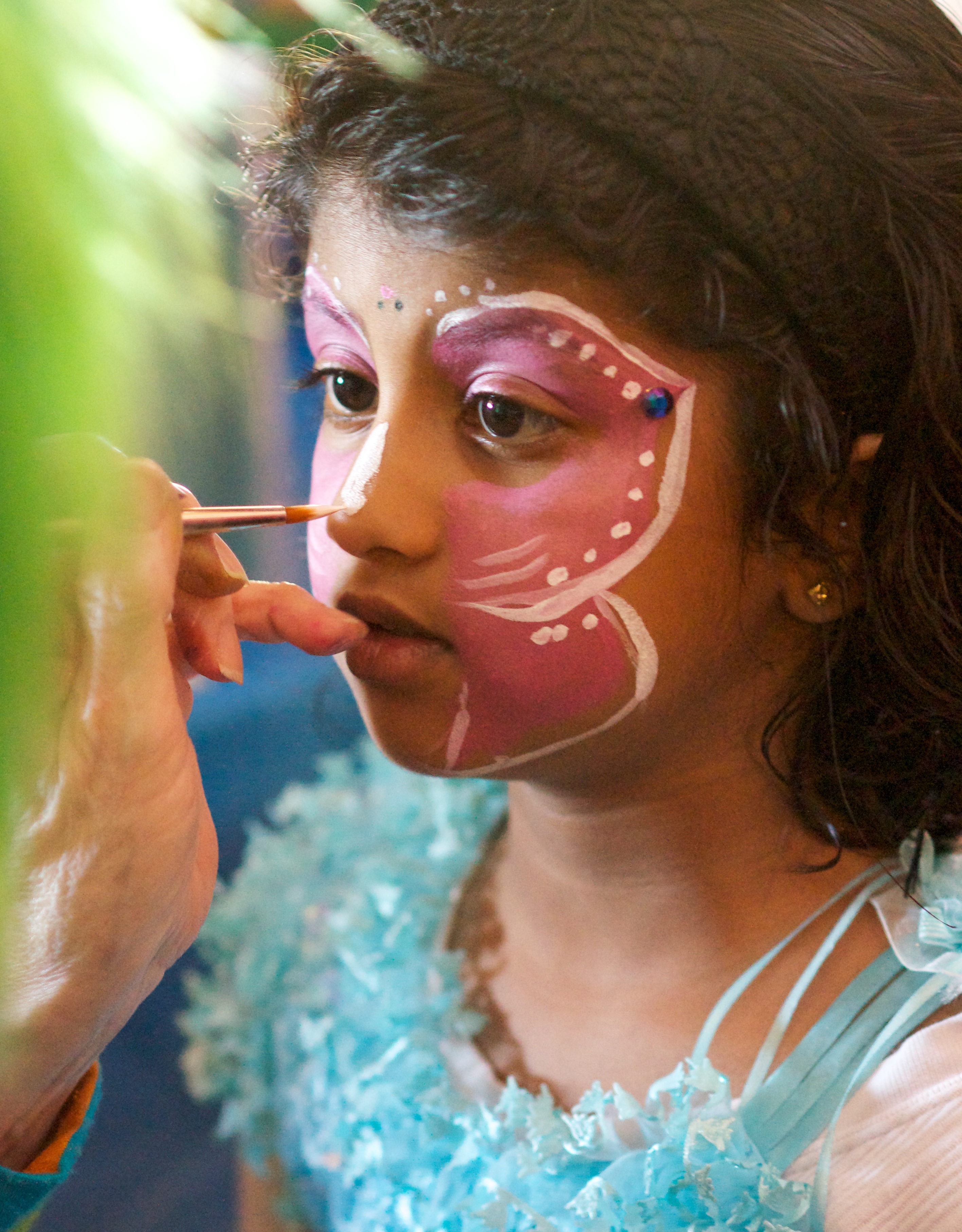 A child getting her face painted with a butterfly design at the Kite Festival.