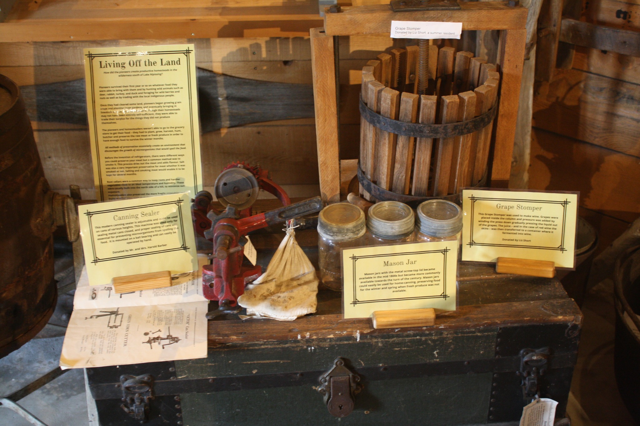 A display of cooking and winemaking implements and informational cards at the Nipissing Township Museum.