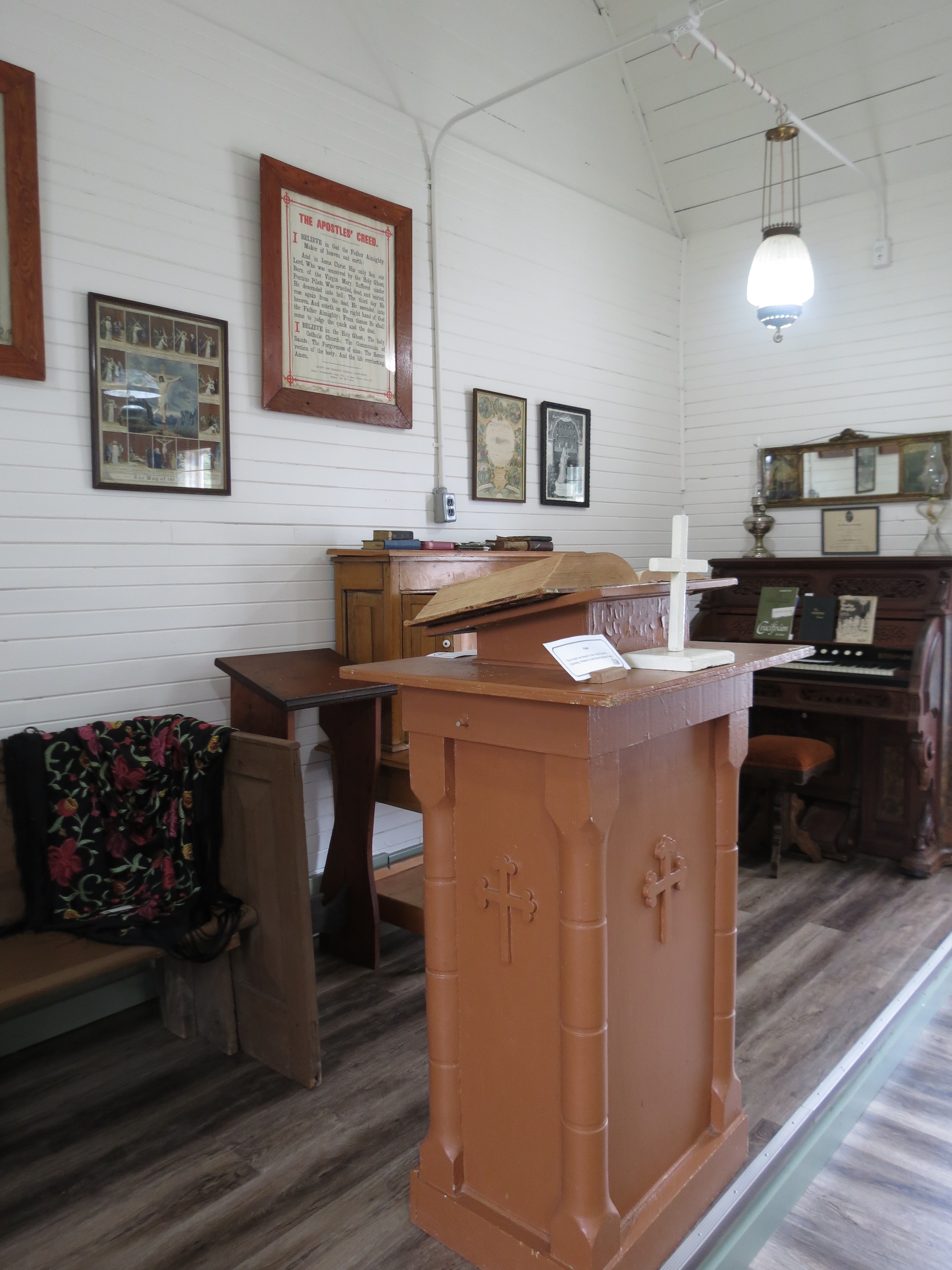 Artifacts in the Nipissing Township Museum, such as an antique wooden church lecturn, organ, and bench.