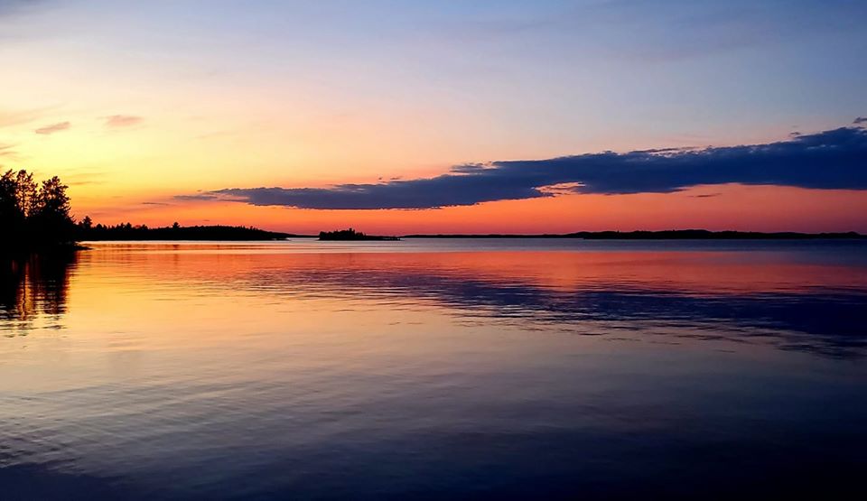 Lake Wanapitei lit up with an orange sunset.