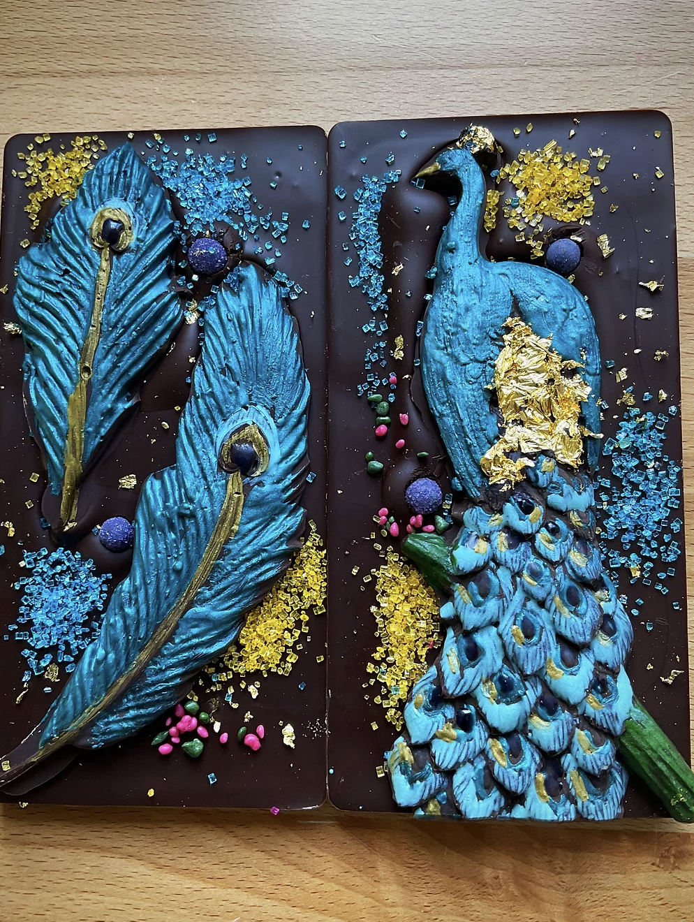 Two dark chocolate bars with an iridescent blue peacock design. 