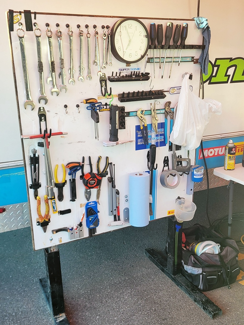 a stand-up pegboard with rows of motorbike repair tools mounted neatly to it.