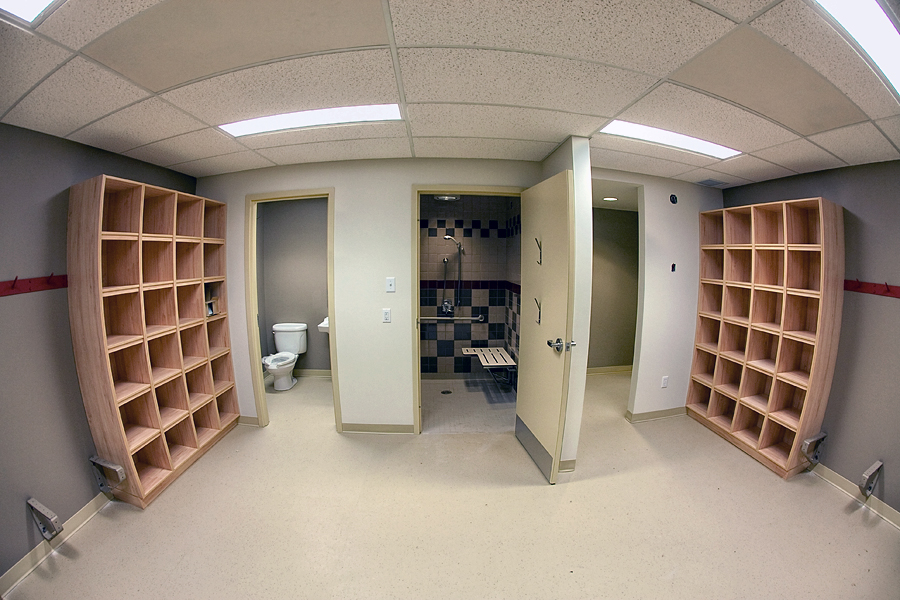 a wide view of the dressing rooms at the Porcupine Ski Runners which features shelves with cubby holes on either side and three doors leading to the bathroom, change room and shower