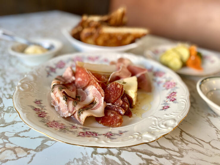 an attractive plate of meats and cheeses, with other dishes in the background.