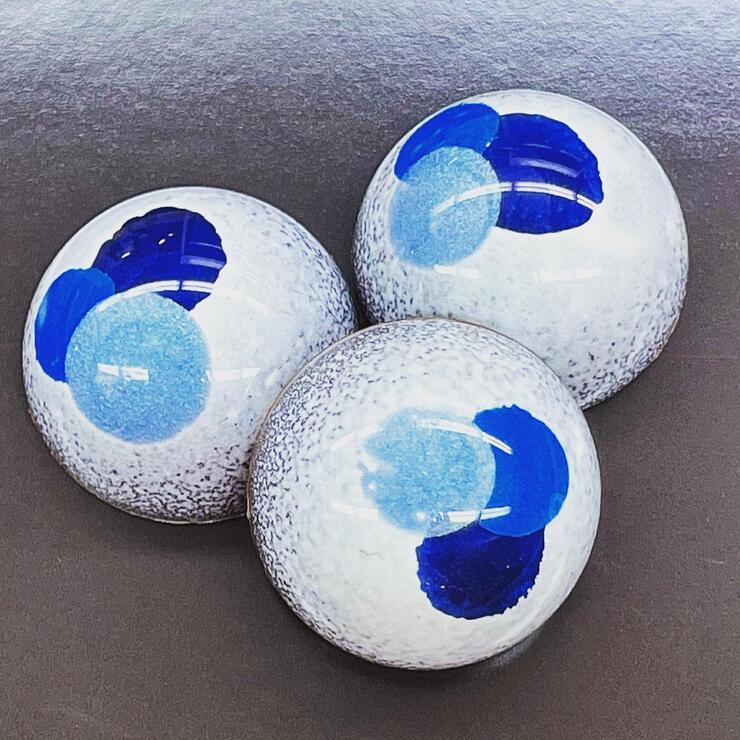 3 round chocolates with a white and blue pattern. 
