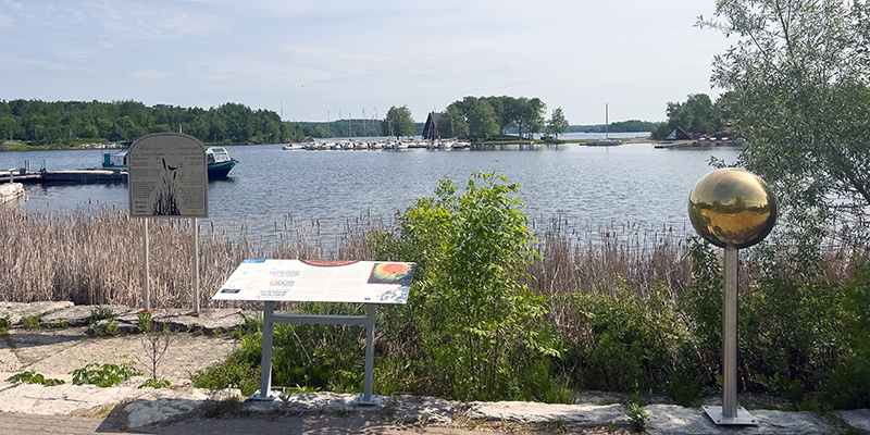 An interpretive panel on a path by a lake. 
